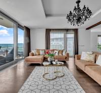 A stylish living room in a 4-room apartment with a sofa, chandelier, and a view of the terrace.