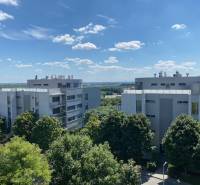 A view of modern apartment buildings in Bratislava - Karlova Ves surrounded by greenery and a blue sky.