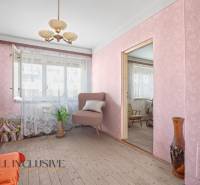 A room in a family house with wallpaper, an armchair, and floral decorations.