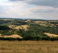 Hilly landscape with forests and open spaces, ideal for rural living.
