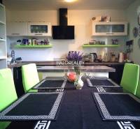 Kitchen in a family house with a dining table, green chairs, and kitchen equipment.