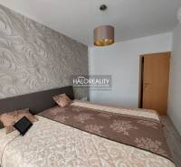 A bedroom in a 3-room apartment with patterned wallpaper and beds with blankets.