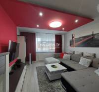 Living room in a 3-room apartment with a sofa, TV, and red decorations.