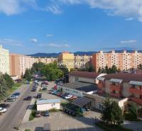 A view of the housing estate in Prievidza with panel buildings and parked cars.