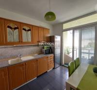 A kitchen with a wooden cabinet in a 3-room apartment, with access to a balcony.