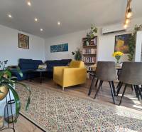 Living room in a 4-room apartment with a sofa, yellow armchair, and wooden furniture.
