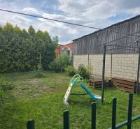The garden of a 4-room apartment in Kočovce with a swing and greenery.