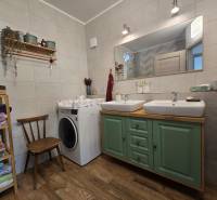 The bathroom in the four-room apartment has two sinks, a washing machine, and shelves with towels.
