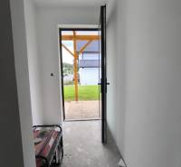 A hallway in a family house with open doors, view out to the garden.