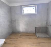 A bathroom in a family house with tiles, ready for installation, light through a small window.