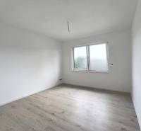The interior of a room in a family house with white walls and light wood flooring.