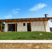 A family house in Malé Kršteňany with a wooden pergola and a lawn on a slope.