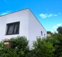 A family house in Malé Kršteňany with greenery and a blue sky in the background.