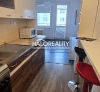 Studio apartment with a kitchen featuring bar stools and a view of the street.