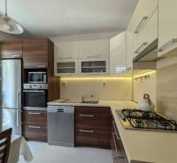 A kitchen in a 4-room apartment with wooden cabinets, a stove, and a refrigerator.