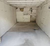 An empty garage interior with walls and shelves, with cracked plaster.