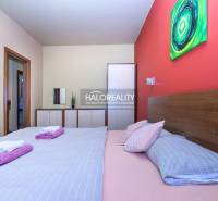 Bedroom with a double bed and an artistic painting in a 2-room apartment.