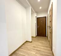 Hallway in a 2-room apartment with wooden flooring and white walls.