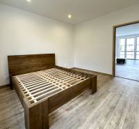 Bedroom in a 2-room apartment with wooden flooring and a bed without a mattress.