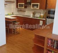 A kitchen in a two-room apartment with wooden cabinets and a bar counter.