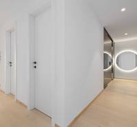 A hallway with a wooden floor, a round mirror, and white doors in a 2-room apartment.