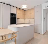 A kitchen in a 2-room apartment with wooden cabinets, a kitchen island, and a dining table.