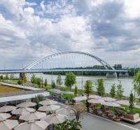Bridge in Bratislava - Old Town, with a view of the river and outdoor seating.
