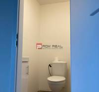 A toilet in a white space with a toilet bowl and a sink. Commercial premises.