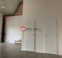 Empty commercial spaces with white doors and exposed pipes on the wall.