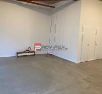 Spacious commercial spaces with concrete flooring, white walls, and an orange pipe on the ceiling.