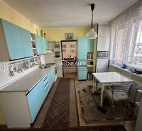 A kitchen in a 3-room apartment with blue cabinets and a dining table.