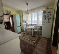 A kitchen in a 3-room apartment with a dining table, refrigerator, and gas stove.