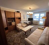 A stylish living room in a 3-room apartment with a sofa, an armchair, and curtains.