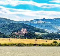 Picturesque scenery of agricultural and forest lands near Lučenec with castle ruins in the middle.