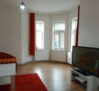 Living room with a sofa, television, table, and wooden decor flooring in a family house.