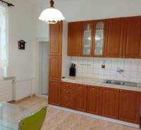 A family house with a kitchen, wooden cabinets, and a pendant light above a glass table.