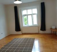 A room in a family house with a wooden decor floor, curtains, and a carpet.