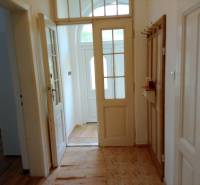 A hallway in a family house with white doors and tiles.