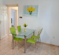Dining area in a family house with a glass table and green chairs.