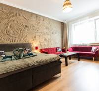 A room in a 2-room apartment with a bed, red sofas, and a decorative relief on the wall.