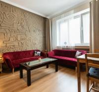 Living room in a two-room apartment with a patterned wall and red sofas.