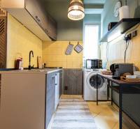 Kitchen in a 2-room apartment with a cooktop, washing machine, and coffee maker.