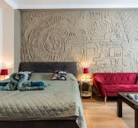 A stylish bedroom with a decorative wall, a bed, and a red sofa in a 2-room apartment.