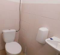 A restroom with a toilet, sink, and soap dispenser in an industrial building.
