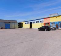 Colorful warehouse and hall buildings in Trnava with a parking lot and cars.