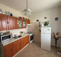 A kitchen in a 3-room apartment with a wooden cabinet, a white refrigerator, and ceramic decorations.