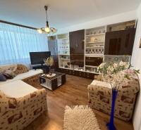 Living room in a three-room apartment with a comfortable couch, a table, and a spacious wall cabinet.