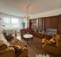 A living room with brown furniture and a couch in a three-room apartment, decorations on the wall.