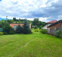 A grassy plot for living in the village of Bodovce surrounded by houses and trees.