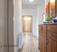 Hallway of a family house with entrance doors, a wooden chest of drawers, and wall decorations.